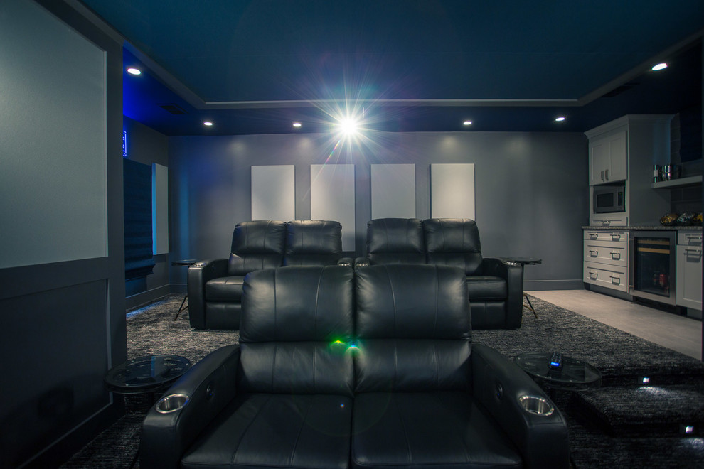 Cette photo montre une grande salle de cinéma tendance fermée avec un mur gris, moquette, un écran de projection et un sol bleu.