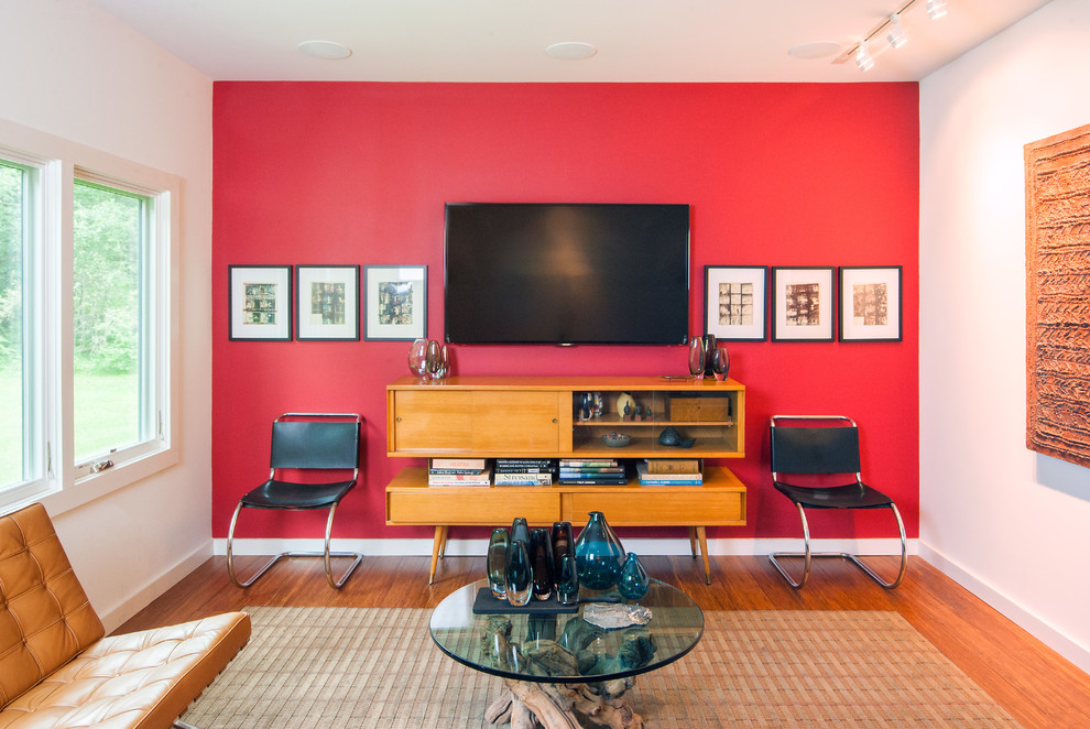 Cette photo montre une salle de cinéma rétro avec un mur rouge, parquet en bambou et un téléviseur fixé au mur.