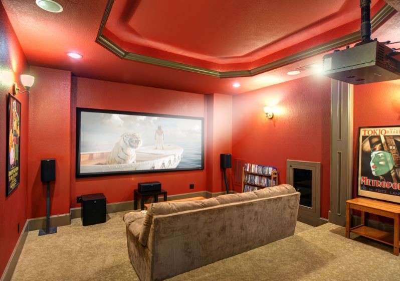 Стильный дизайн: изолированный домашний кинотеатр в стиле рустика с красными стенами, ковровым покрытием и проектором - последний тренд