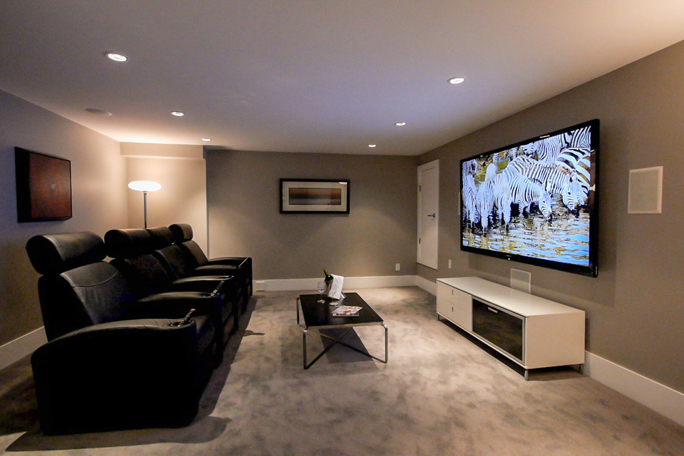 Diseño de cine en casa cerrado actual de tamaño medio con paredes beige, moqueta y televisor colgado en la pared