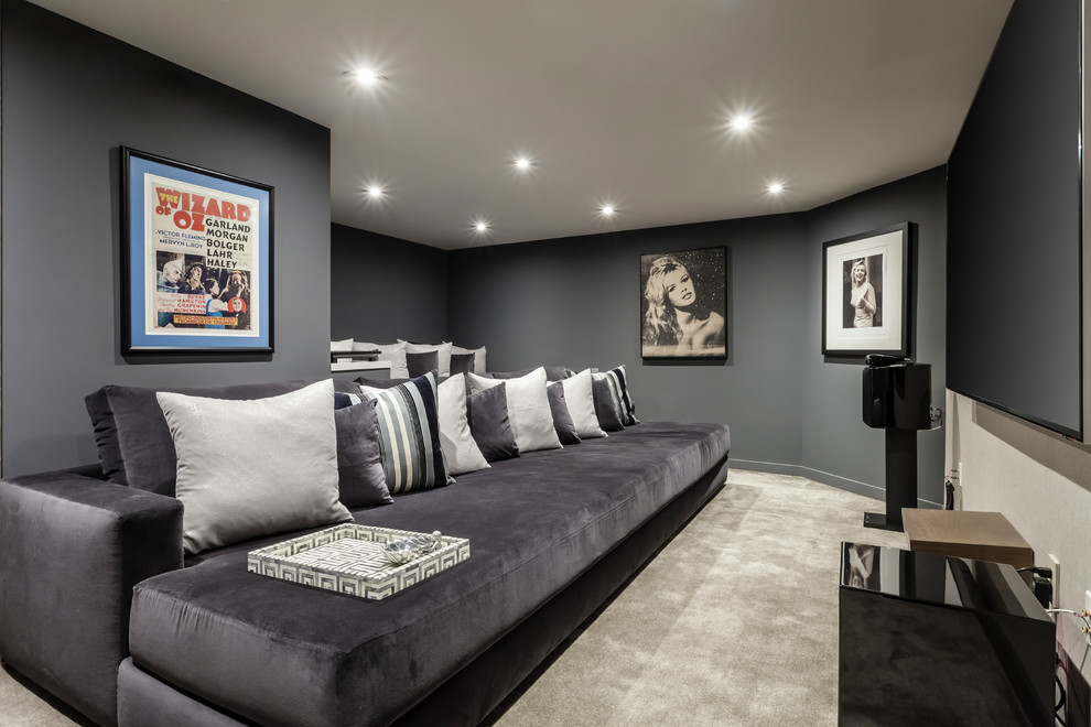 Modelo de cine en casa cerrado contemporáneo con paredes grises, moqueta, televisor colgado en la pared y suelo gris