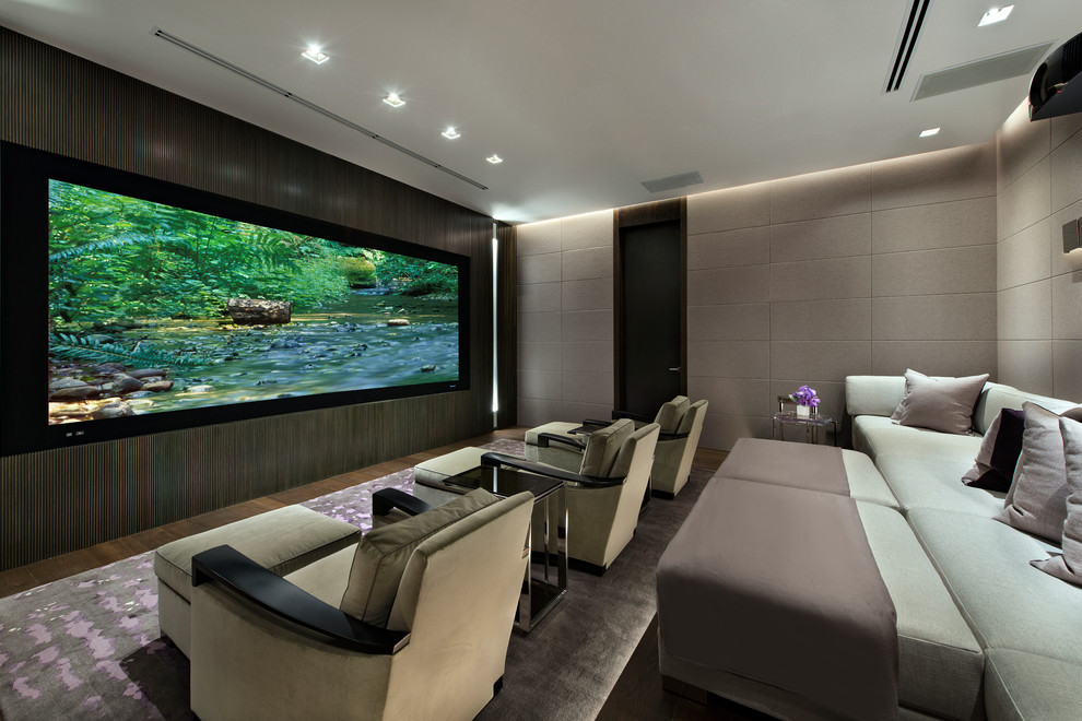 Cette image montre une grande salle de cinéma design ouverte avec un mur gris, parquet foncé, un écran de projection et un sol marron.