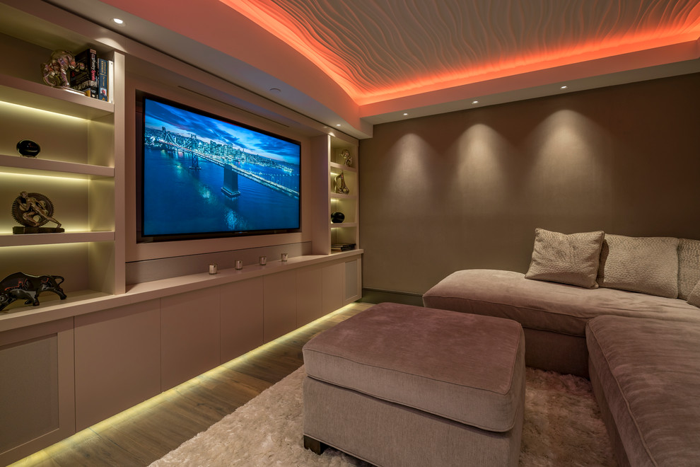 Inspiration pour une salle de cinéma design avec un mur beige, un sol en bois brun et un téléviseur encastré.