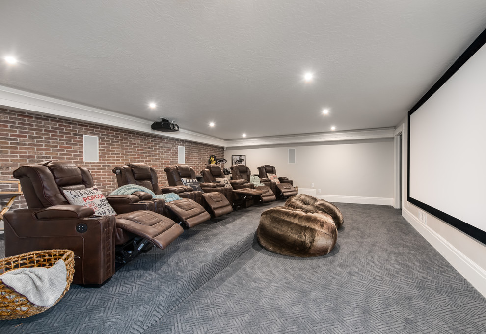 Diseño de cine en casa cerrado tradicional renovado grande con paredes grises, moqueta, pantalla de proyección y suelo gris