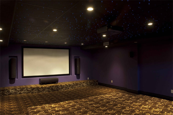 Idées déco pour une salle de cinéma contemporaine fermée avec un mur violet, moquette, un écran de projection et un sol multicolore.