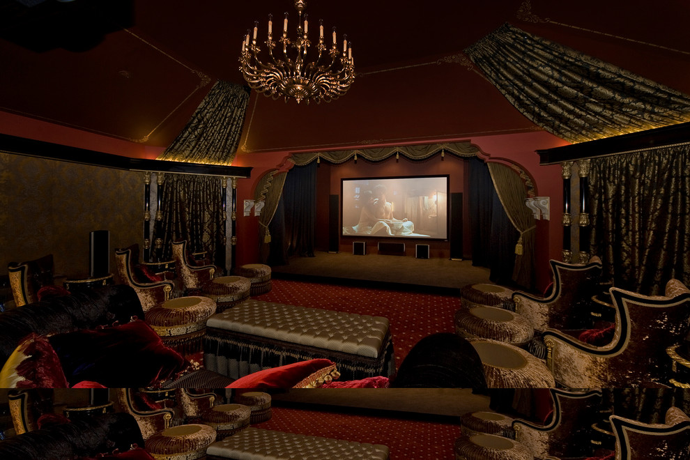 На фото: огромный изолированный домашний кинотеатр в классическом стиле с красными стенами, ковровым покрытием, проектором и красным полом с