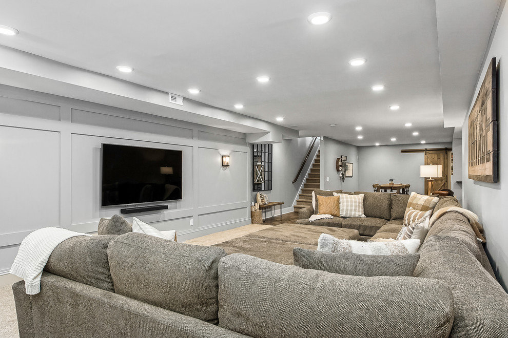Imagen de cine en casa abierto de estilo de casa de campo grande con paredes grises, moqueta, televisor colgado en la pared y suelo beige
