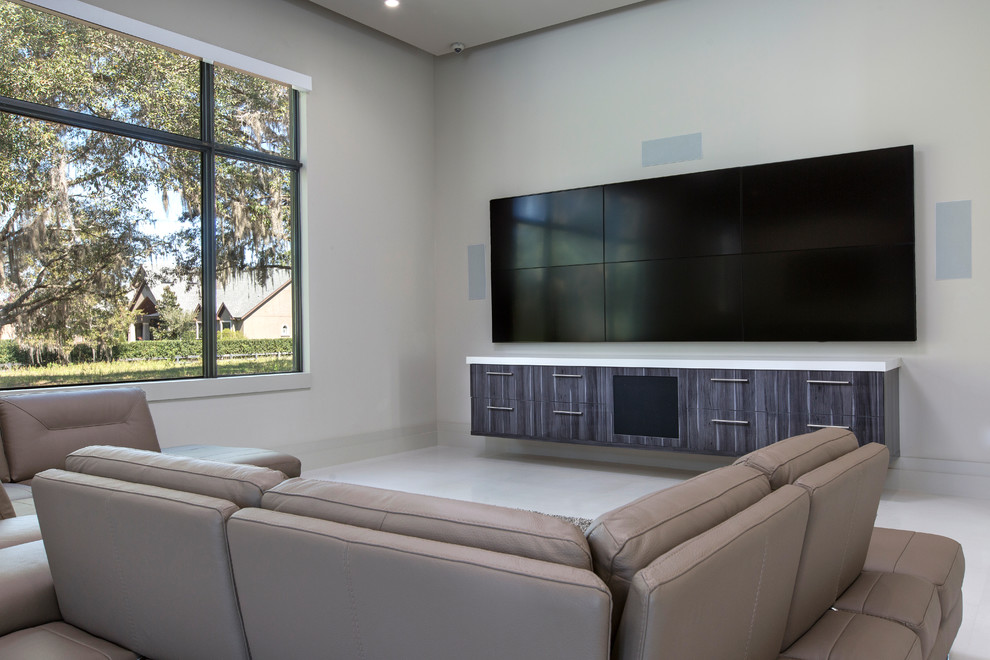 Imagen de cine en casa abierto minimalista de tamaño medio con paredes blancas, suelo de piedra caliza, televisor colgado en la pared y suelo blanco