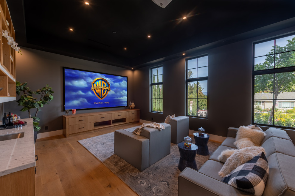 Medium sized traditional enclosed home cinema in Los Angeles with grey walls, medium hardwood flooring, a projector screen and brown floors.
