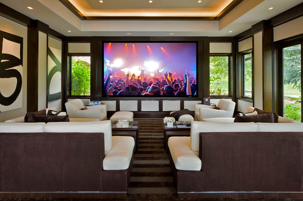 This is an example of a traditional home cinema in Denver with beige walls, a projector screen and brown floors.