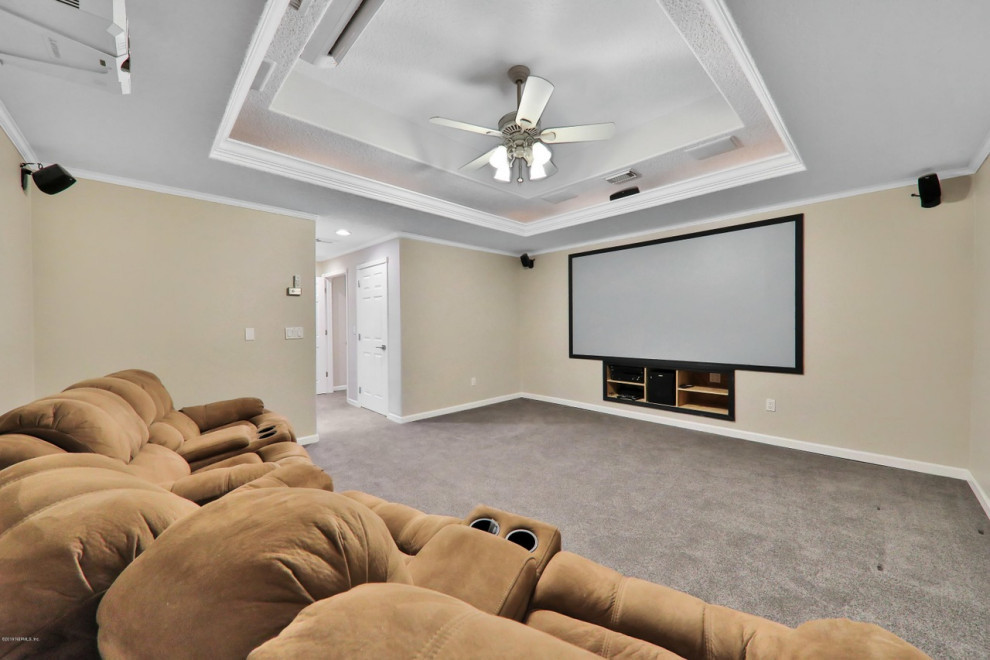 Exemple d'une grande salle de cinéma chic fermée avec un mur beige, moquette, un sol gris et un téléviseur encastré.