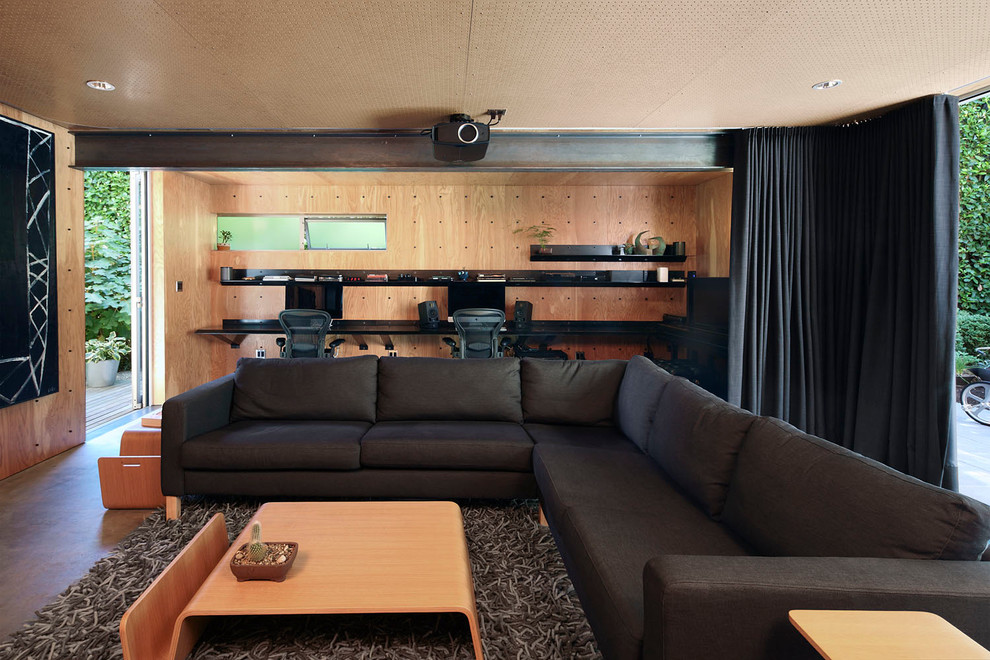 На фото: изолированный домашний кинотеатр среднего размера в современном стиле с коричневыми стенами, бетонным полом, проектором и коричневым полом с