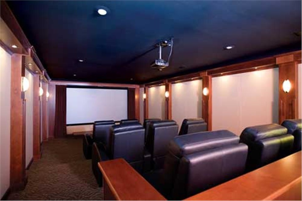 This is an example of a large mediterranean enclosed home cinema in Miami with brown walls, carpet, a projector screen and brown floors.