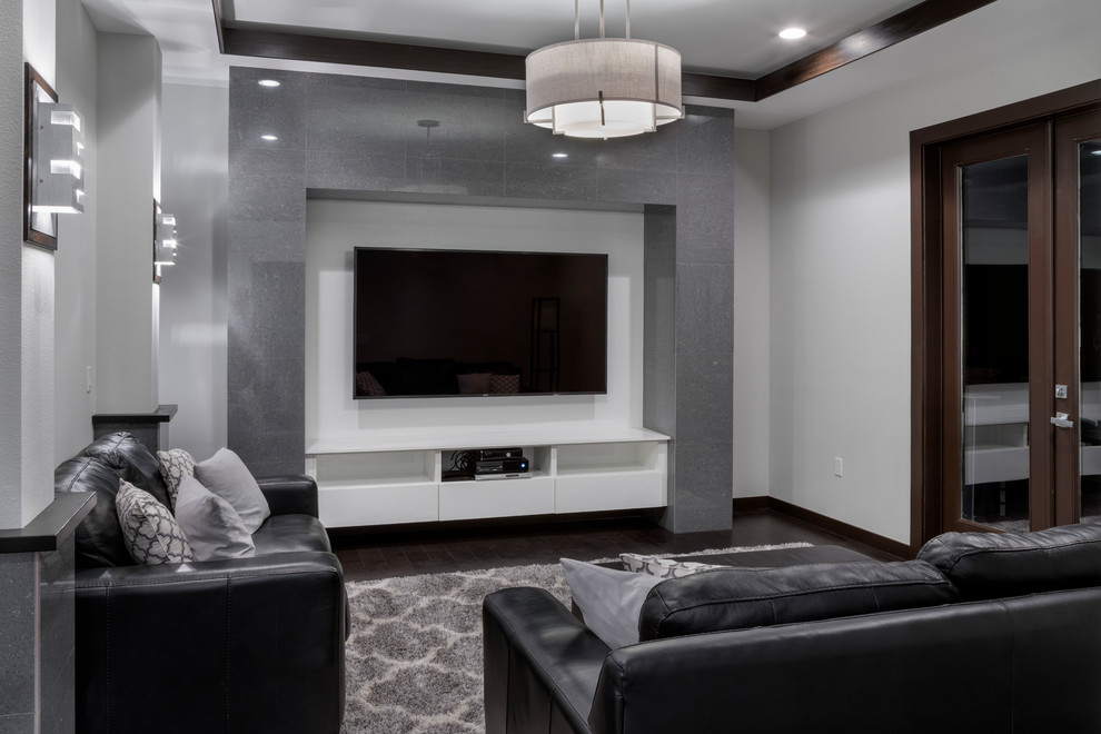 Foto på ett mellanstort funkis öppen hemmabio, med grå väggar, mörkt trägolv, en väggmonterad TV och brunt golv