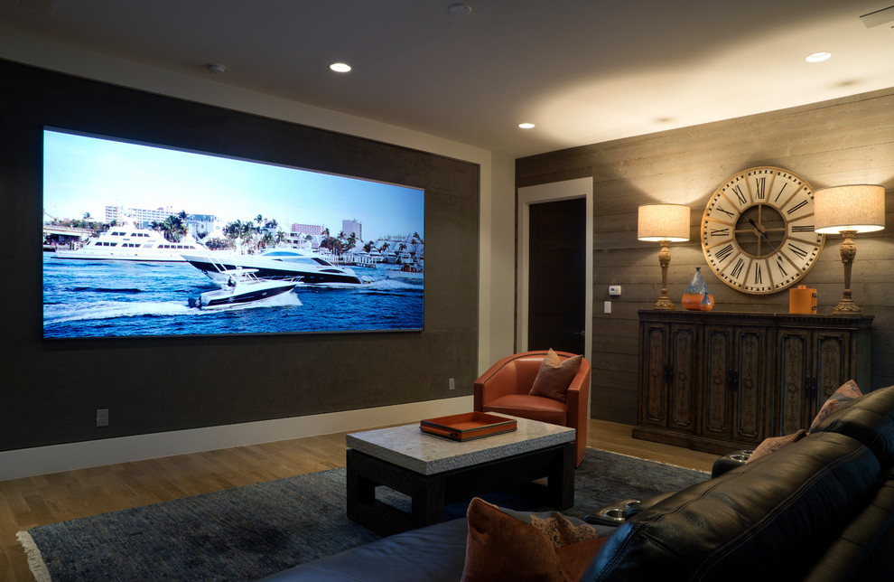 Diseño de cine en casa cerrado contemporáneo de tamaño medio con paredes grises, suelo de madera clara, televisor colgado en la pared y suelo beige