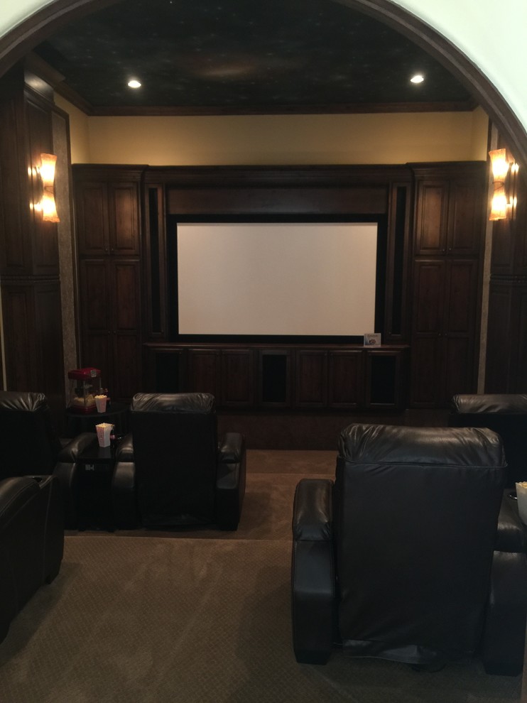 Imagen de cine en casa cerrado clásico de tamaño medio con paredes beige, moqueta, pantalla de proyección y suelo marrón
