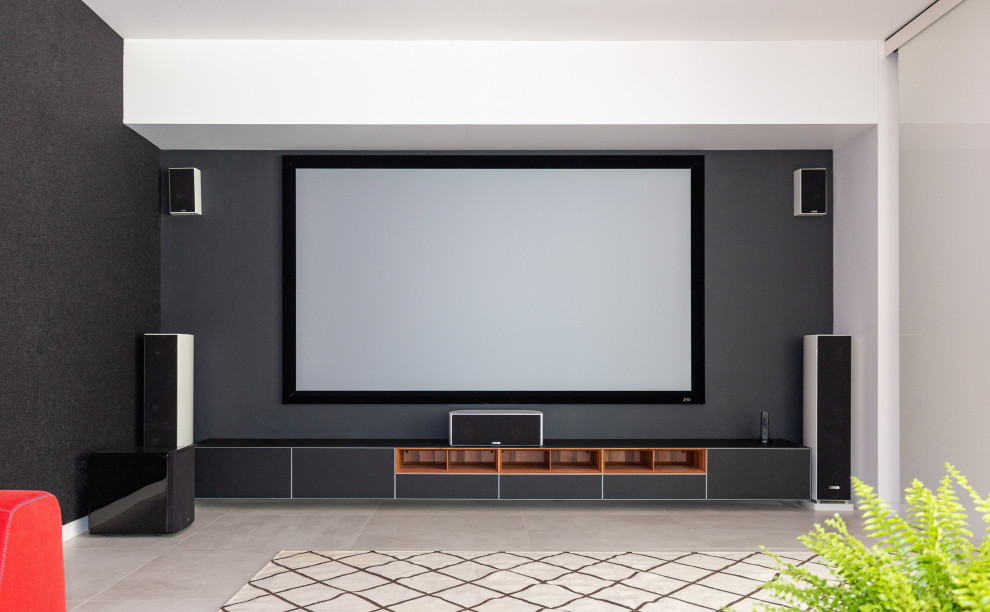 Aménagement d'une grande salle de cinéma ouverte avec un mur noir, un sol en carrelage de porcelaine, un écran de projection et un sol gris.
