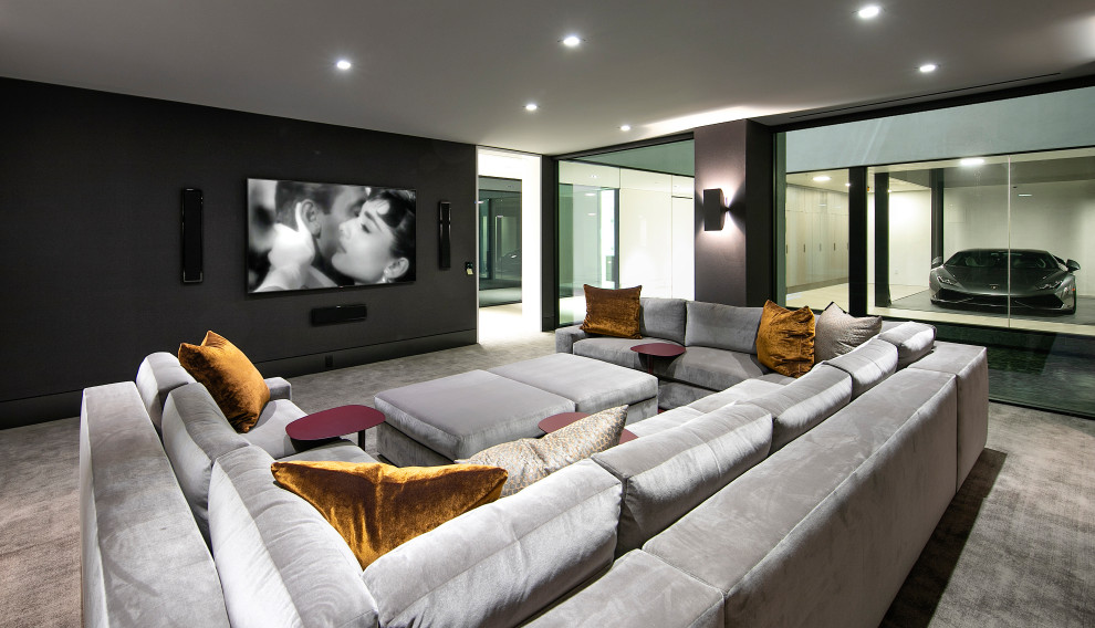 Immagine di un home theatre design con pareti nere, moquette, TV a parete e pavimento grigio