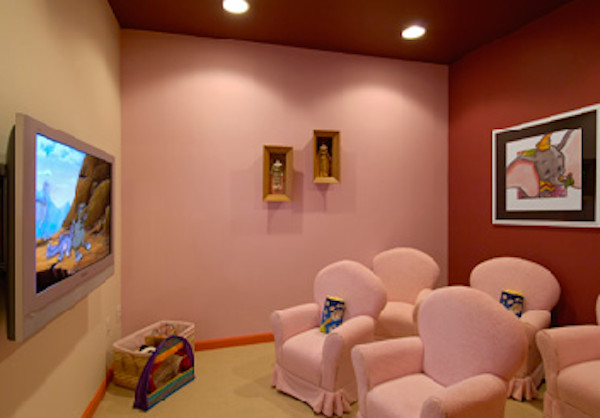 Foto di un home theatre chiuso con pareti rosa, moquette e TV a parete
