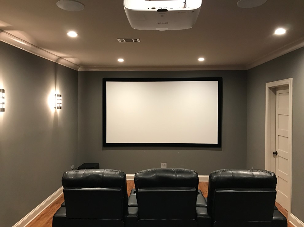 This is an example of a medium sized traditional enclosed home cinema in Atlanta with beige walls, medium hardwood flooring, a projector screen and brown floors.