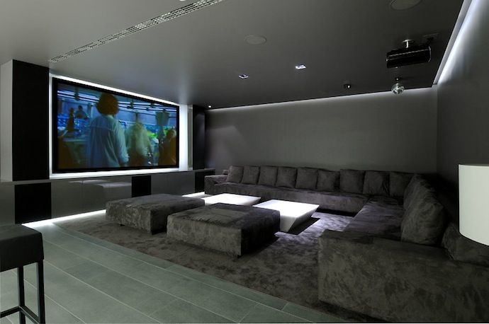 Imagen de cine en casa cerrado moderno grande con paredes grises, suelo de baldosas de cerámica y pantalla de proyección