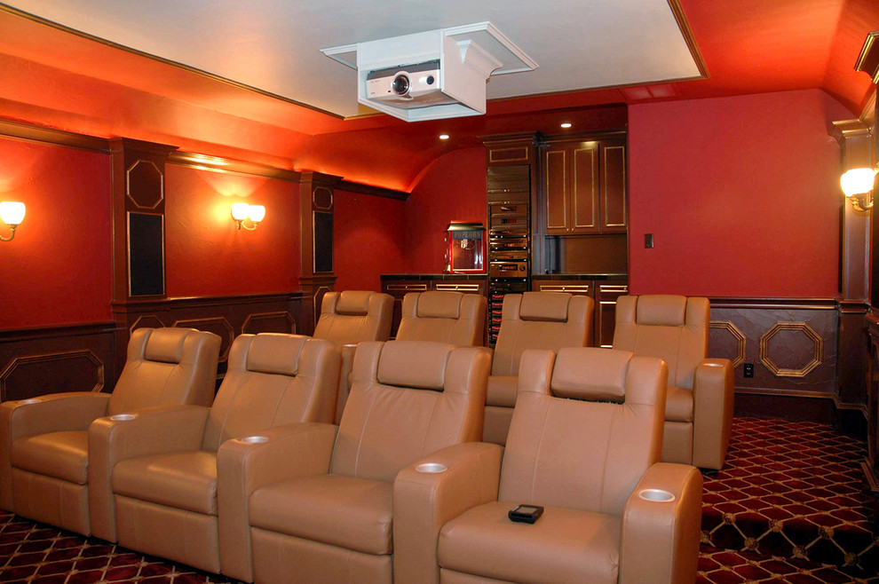 Diseño de cine en casa cerrado clásico grande con paredes rojas, moqueta, pantalla de proyección y suelo multicolor