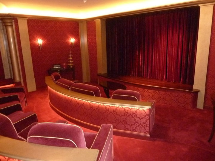 Idee per un ampio home theatre boho chic chiuso con pareti rosse, moquette, schermo di proiezione e pavimento rosso