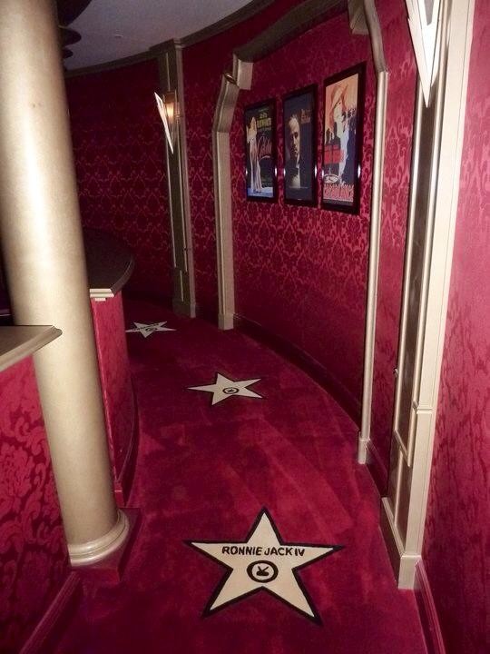 Exemple d'une très grande salle de cinéma éclectique fermée avec un mur rouge, moquette, un écran de projection et un sol rouge.