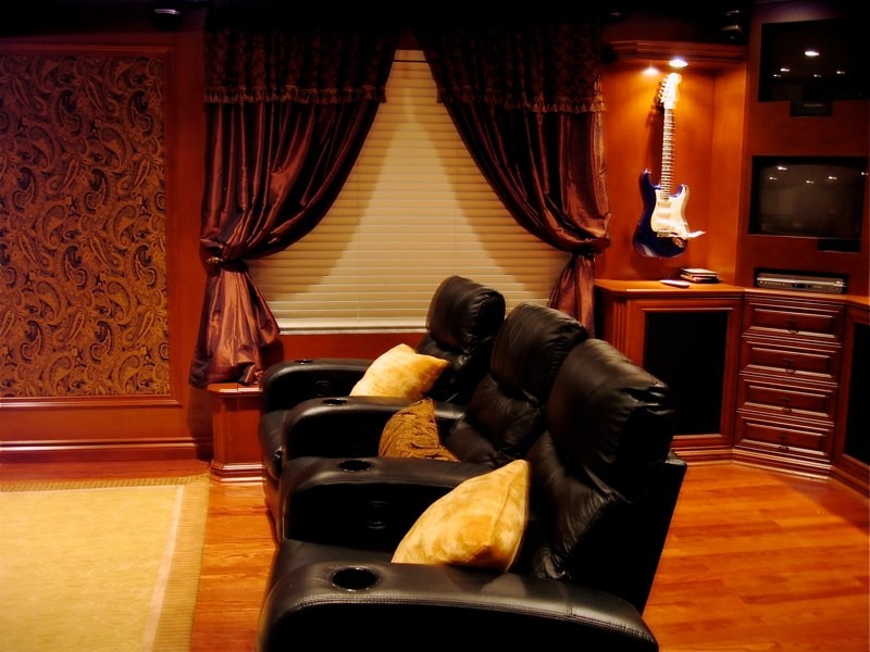 Стильный дизайн: большой изолированный домашний кинотеатр в классическом стиле с коричневыми стенами, темным паркетным полом, проектором и коричневым полом - последний тренд