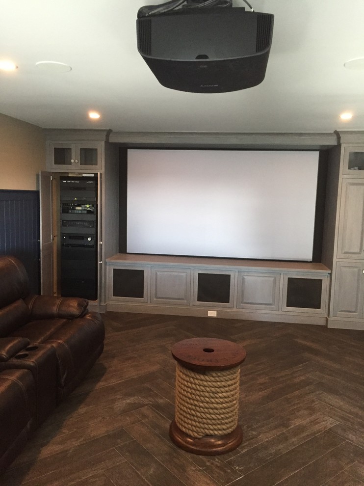 Modelo de cine en casa cerrado moderno grande con paredes beige, pantalla de proyección y suelo de madera oscura