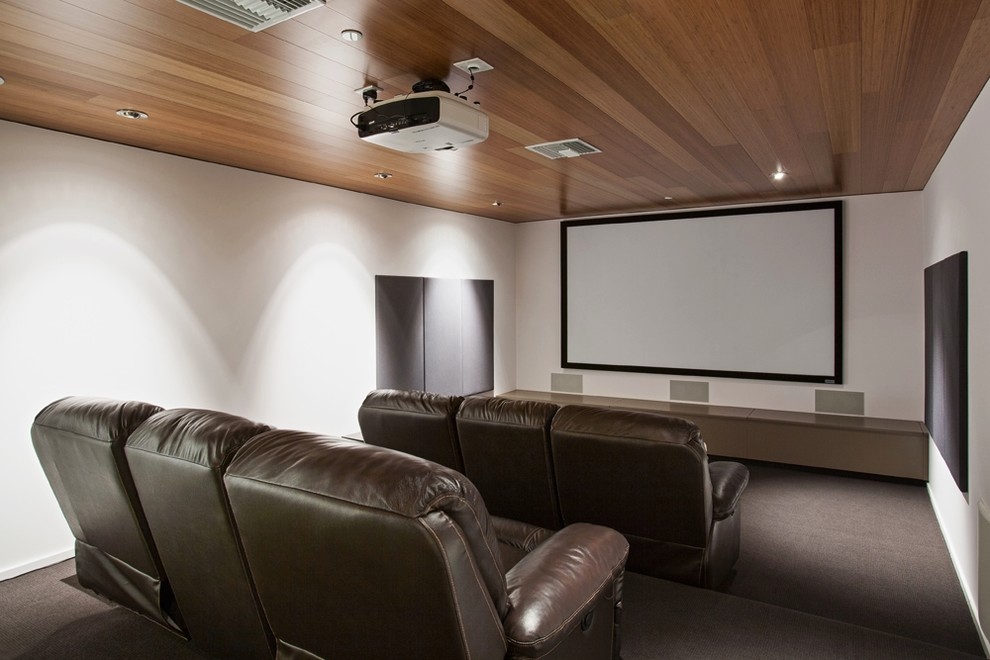 Пример оригинального дизайна: большой изолированный домашний кинотеатр в стиле модернизм с белыми стенами, ковровым покрытием и проектором