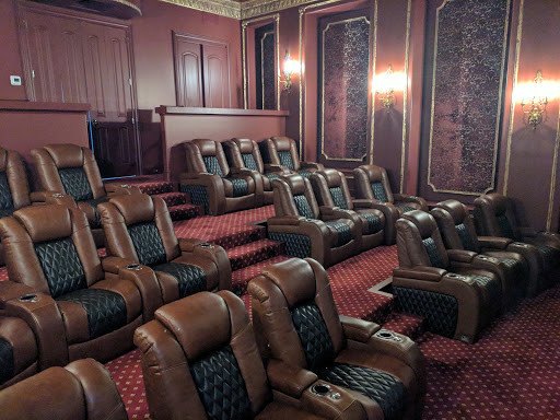 Aménagement d'une grande salle de cinéma victorienne fermée avec un mur marron, moquette, un écran de projection et un sol rouge.