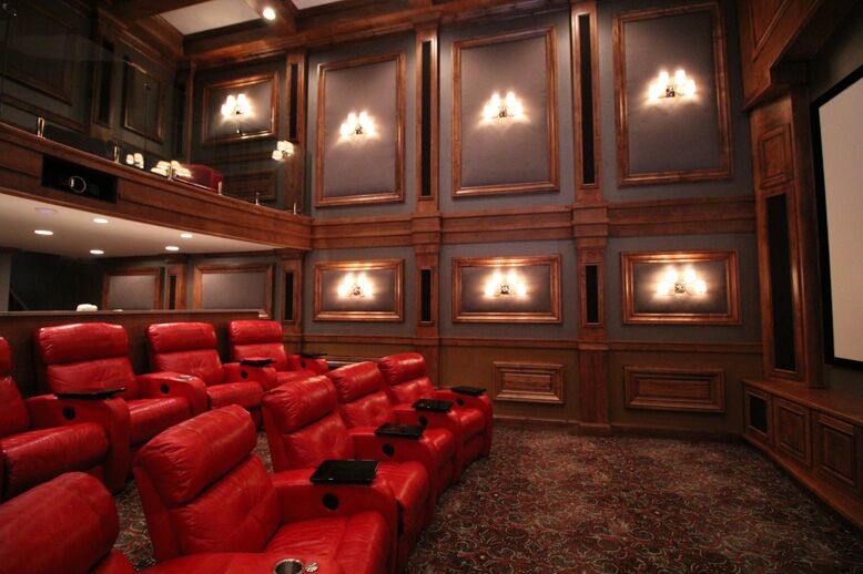Cette image montre une grande salle de cinéma fermée avec un mur multicolore, moquette, un écran de projection et un sol multicolore.