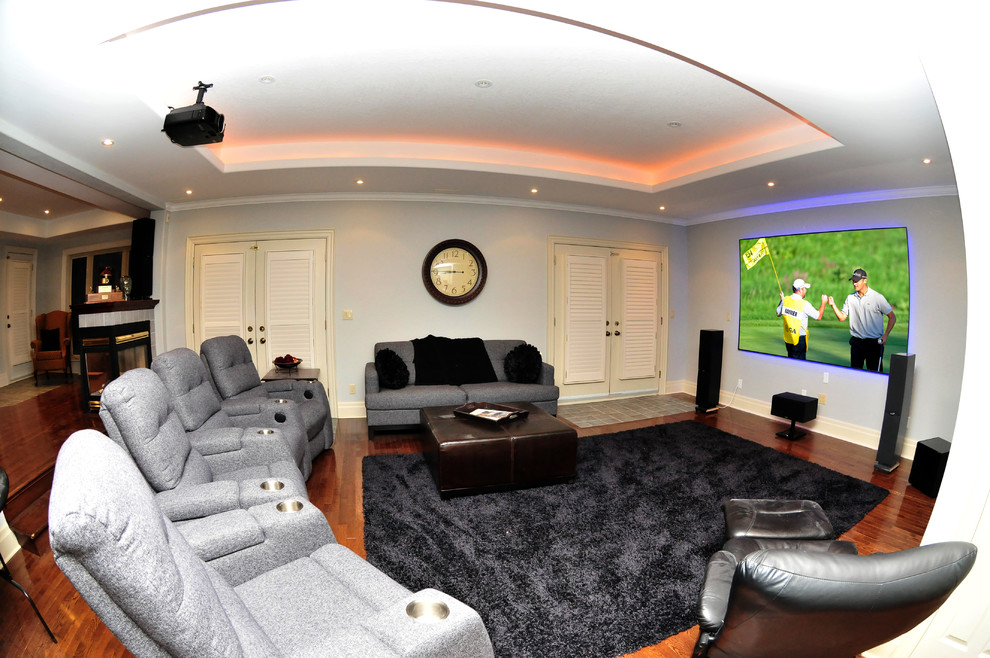 Imagen de cine en casa actual con paredes beige, suelo de madera en tonos medios y pantalla de proyección
