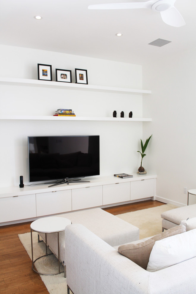 Modelo de cine en casa abierto minimalista de tamaño medio con paredes blancas, suelo de bambú y pared multimedia