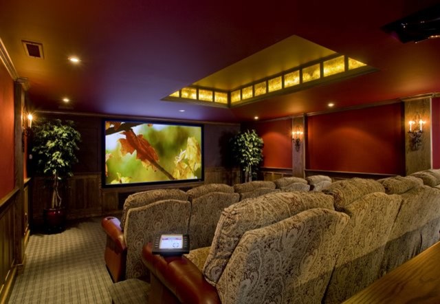 Стильный дизайн: большой изолированный домашний кинотеатр в классическом стиле с красными стенами, ковровым покрытием, проектором и разноцветным полом - последний тренд