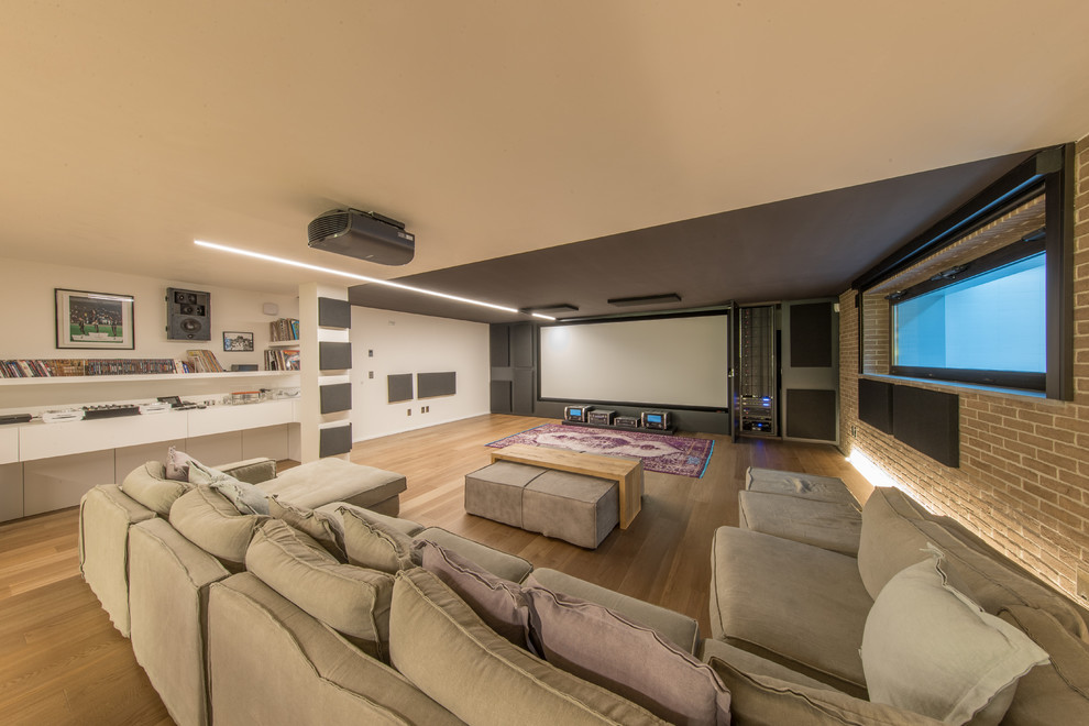 Photo of a large contemporary home cinema in Miami with white walls, a projector screen, light hardwood flooring and beige floors.