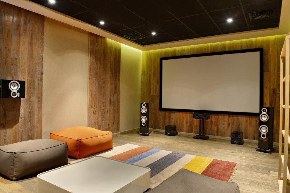 Photo of a large contemporary enclosed home cinema in Denver with multi-coloured walls, light hardwood flooring, a projector screen and brown floors.