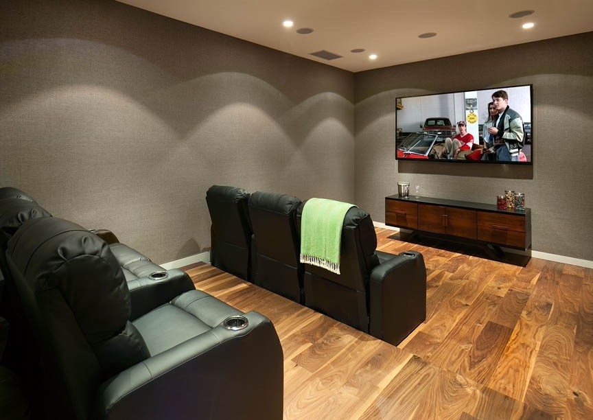 Design ideas for a medium sized contemporary enclosed home cinema in Los Angeles with grey walls, medium hardwood flooring and a wall mounted tv.