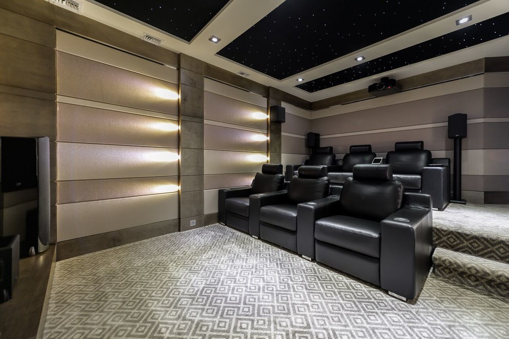 На фото: большой изолированный домашний кинотеатр в стиле неоклассика (современная классика) с ковровым покрытием, серым полом, проектором и серыми стенами
