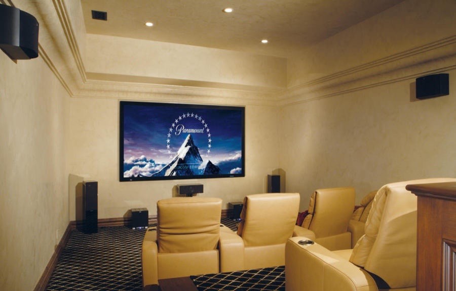 Imagen de cine en casa abierto clásico extra grande con paredes beige, suelo de madera en tonos medios y televisor colgado en la pared