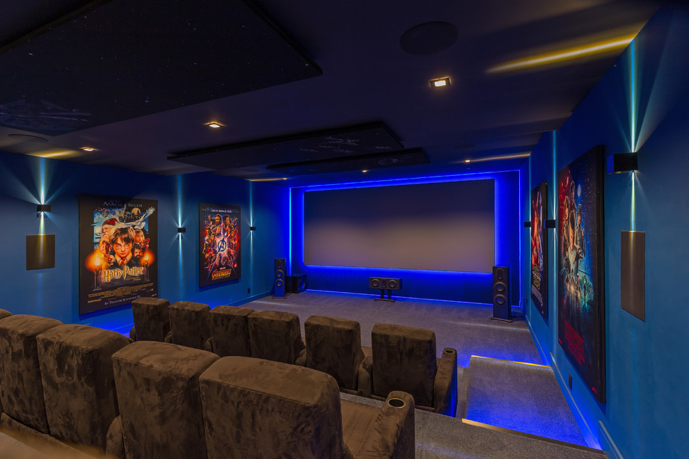 Cette photo montre une très grande salle de cinéma moderne fermée avec un mur bleu, moquette, un écran de projection et un sol gris.