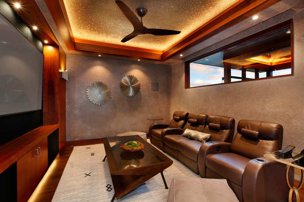 Ejemplo de cine en casa cerrado tropical con pared multimedia, paredes marrones y suelo de madera oscura