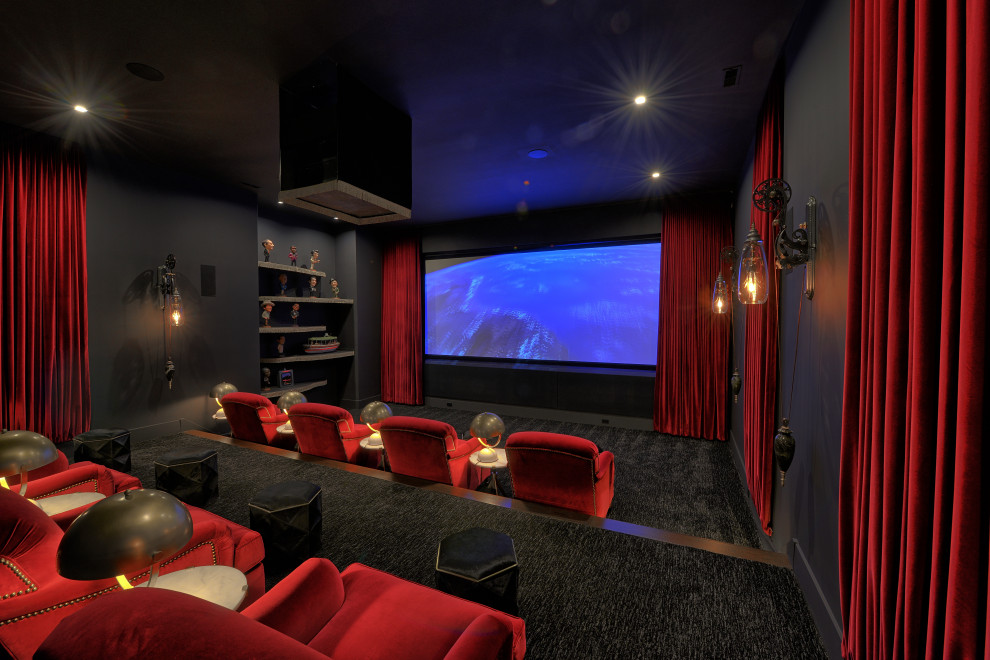 Cette image montre une grande salle de cinéma minimaliste ouverte avec un mur noir, moquette, un écran de projection et un sol multicolore.