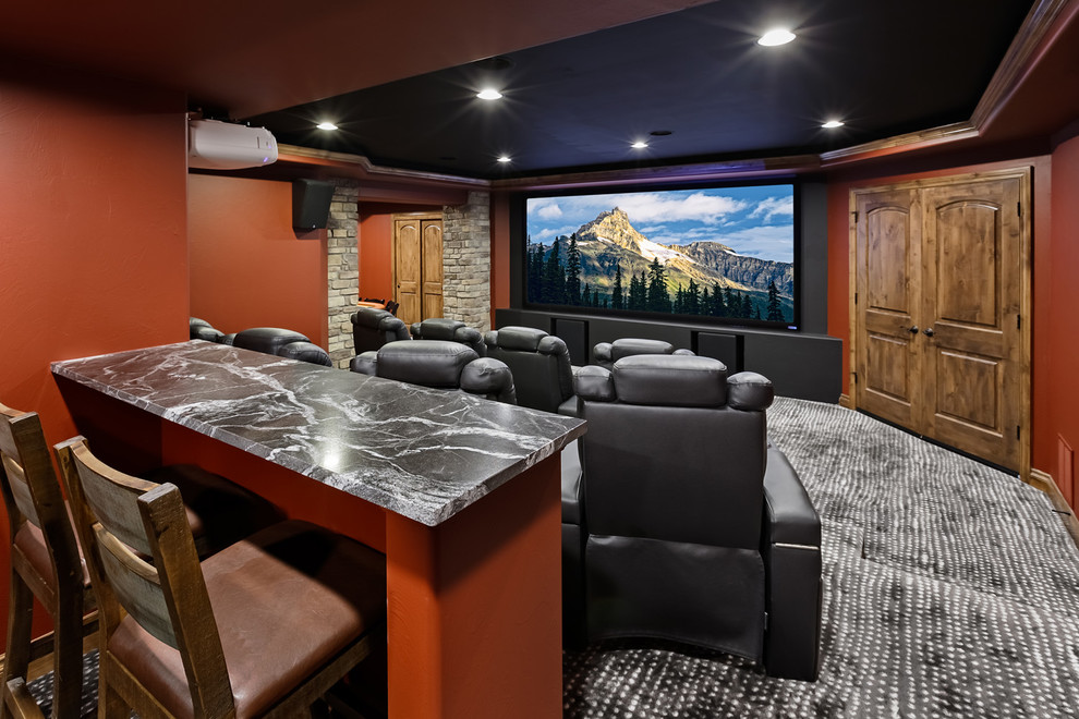 This is an example of a large traditional enclosed home cinema in Denver with orange walls, carpet, a projector screen and grey floors.