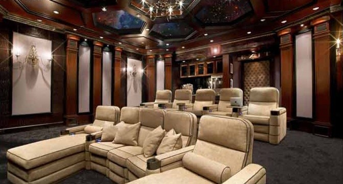 Cette photo montre une grande salle de cinéma chic fermée avec un mur beige, moquette et un écran de projection.