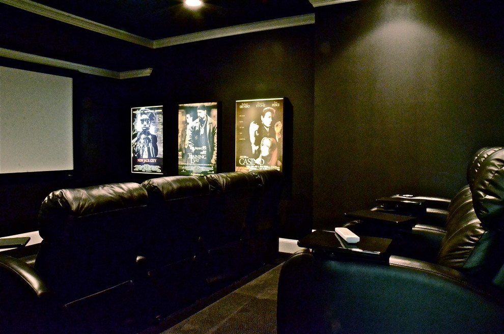 Foto di un grande home theatre minimalista chiuso con pareti nere, moquette, schermo di proiezione e pavimento nero