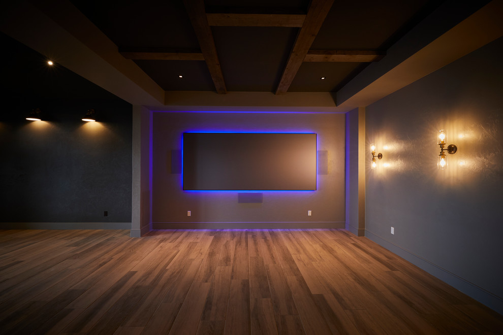 Aménagement d'une grande salle de cinéma contemporaine avec un mur gris, un sol en bois brun et un écran de projection.