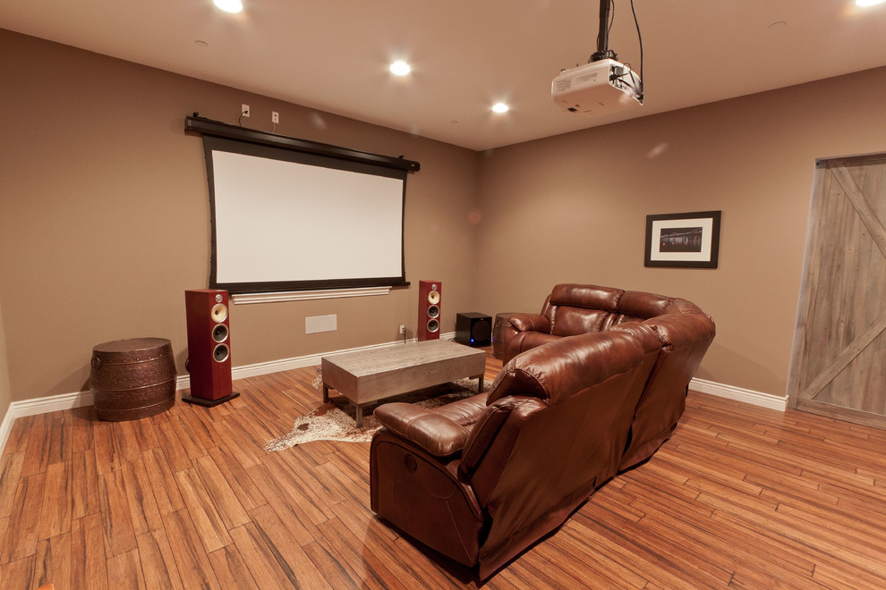 Ejemplo de cine en casa cerrado de estilo americano grande con paredes marrones, suelo de bambú, pantalla de proyección y suelo marrón