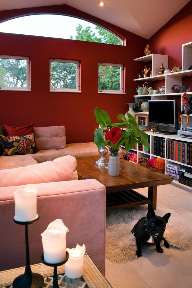 Idéer för att renovera ett mellanstort eklektiskt öppen hemmabio, med röda väggar, kalkstensgolv, en väggmonterad TV och beiget golv